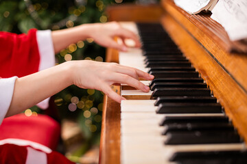 Child in Santa costume playing on a piano, creating Christmas music.