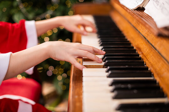 Child in Santa costume playing on a piano, creating Christmas music.
