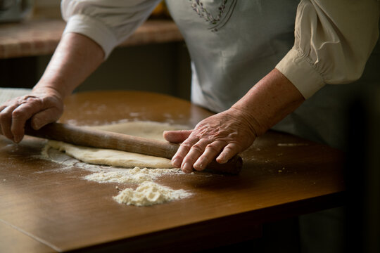 Old woman rolling dough on a table