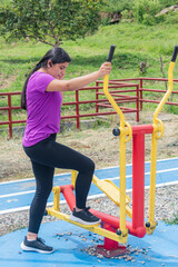 Fototapeta premium Latina Woman Preparing to Use Outdoor Elliptical Trainer