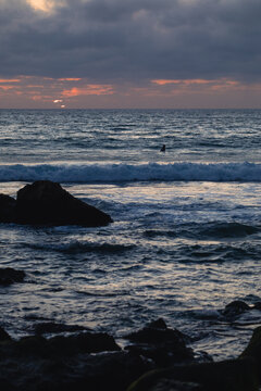 Surfer waiting for waves at sunset in sagres, portugal