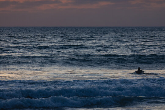 Surfer waiting for the right wave at sunset in the algarve, port