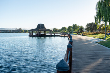 Woman looks out over calm waterfront boardwalk near pagoda and lake reflection, August 8, 2020