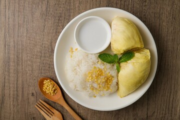 Durian Sticky Rice  with spoon and fork in white plate on wooden background