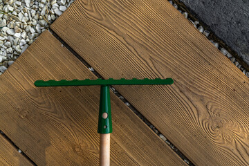New green rakes for raking leaves on the plot placed on the tiles in front of the entrance