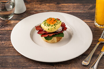 Eggs Benedict with poached egg, bacon, spinach and hollandaise sauce