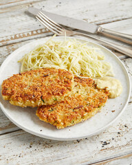 Vegan schnitzel with cabbage apple salad on white plate