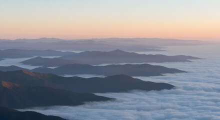 Stacked mountain silhouettes at dawn with warm light and atmospheric haze.









