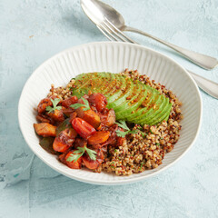 Quinoa bowl with avocado, nuts and tomatoes