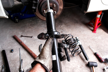  Car Shock Absorber or Strut, A mechanic hand holds a new black shock absorber or strut for...