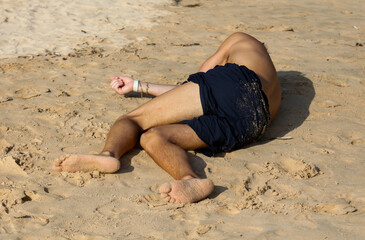 A man is laying on the beach with his legs spread apart