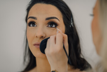 Makeup artist applying eyeliner to model's eyelid