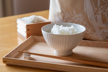 トレイの上の茶碗に盛ったご飯と箸、枡に入った白米と米袋