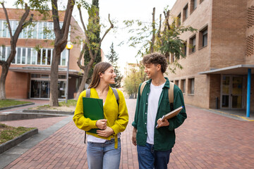 Two smiling students walking and talking on university campus