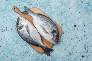 Raw dorado fish on cutting board over blue background