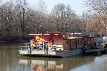 An old, rusty nautical vessel moored on a calm river