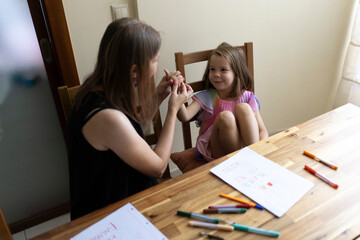 Teacher helping young girl student learning sign language at home