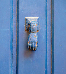 Historic iron door knocker in the shape of a hand on a house door  in Toulouse, France