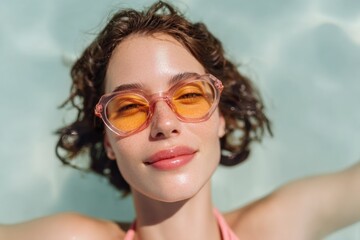 Fototapeta premium A woman wearing pink sunglasses and a pink bikini top