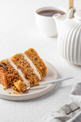 Homemade layered carrot cake with cream cheese, walnuts and spices on a plate with tea