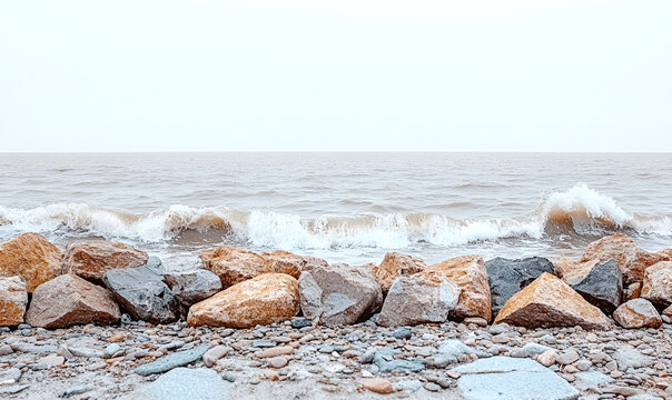 Waves crash against a rocky shoreline, with large boulders in the foreground and the ocean stretching to the horizon under a cloudy sky.
