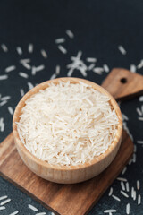 White rice in wooden bowl with scattered grains and wooden spoon
