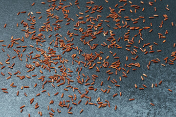 Scattered red rice grains on dark background, top view