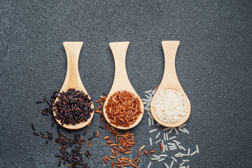 Three types of rice on wooden spoons black red and white grains