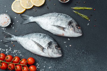 Top view of raw dorado fish with lemon pepper and rosemary on black background
