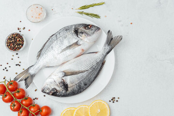 Raw dorado fish with tomatoes lemon and spices on white background