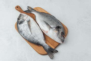 Raw dorado fish on wooden cutting board over white background