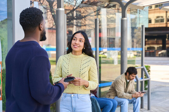 woman waiting at a bus stop while engaging in conversation with a friend