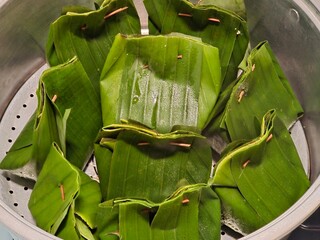 Traditional banana leaf-wrapped steamed snack neatly arranged in stainless pot before cooking...