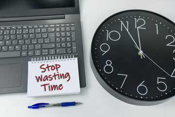 Stop wasting time sign written on the laptop with the clock
