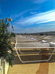 Outdoor promenade boat pool deck onboard modern luxury cruiseship cruise ship ocean liner with sun loungers and deck chairs for guests passengers with ocean views