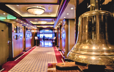 Opulent Art Deco interior architecture inside corridor hallway with metal ship bell close up on modern ocean liner cruiseship cruise ship with carpet and art work