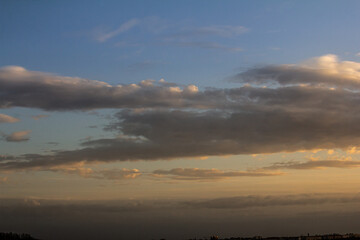 Colorful clouds drift across a serene sky at dusk over a peaceful landscape in the evening