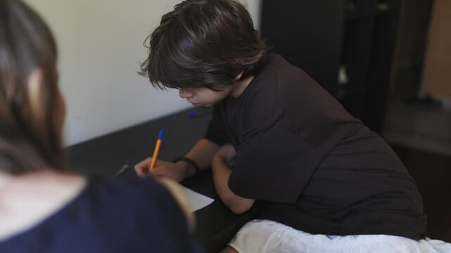 Young boy doing homework, writing on paper at home