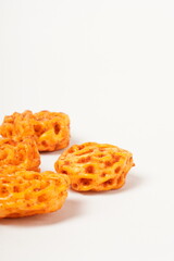 A pile of spicy Indonesian crackers or Kerupuk with spiral twists, coated in red-orange chili powder and rich spices. Bold, flavorful, and appetite-boosting. Photographed against a white background.