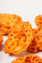 A pile of spicy Indonesian crackers or Kerupuk with spiral twists, coated in red-orange chili powder and rich spices. Bold, flavorful, and appetite-boosting. Photographed against a white background.