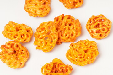 A pile of spicy Indonesian crackers or Kerupuk with spiral twists, coated in red-orange chili powder and rich spices. Bold, flavorful, and appetite-boosting. Photographed against a white background.
