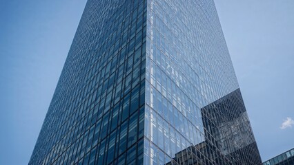 Modern glass skyscraper against a clear blue sky.