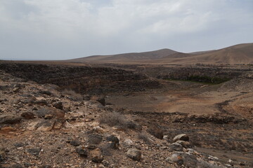 volcanic arid landscapes with trils, cliffs, and scattedred vegetation.
