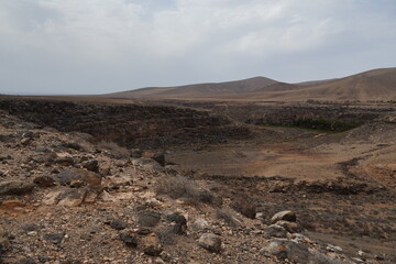 volcanic arid landscapes with trils, cliffs, and scattedred vegetation.