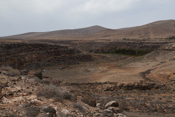 volcanic arid landscapes with trils, cliffs, and scattedred vegetation.