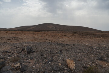 volcanic arid landscapes with trils, cliffs, and scattedred vegetation.