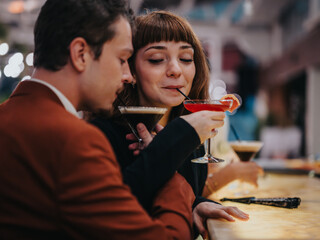 Young couple sharing a romantic evening at a stylish bar. They are sipping cocktails and enjoying...