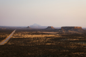 Vast desert plain in Ugab, Namibia, with striking mesa formations reminiscent of the American West under soft dusk light.