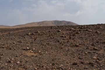 volcanic arid landscapes with trils, cliffs, and scattedred vegetation.