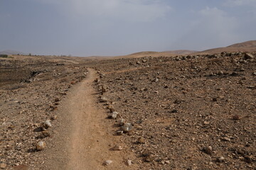 volcanic arid landscapes with trils, cliffs, and scattedred vegetation.